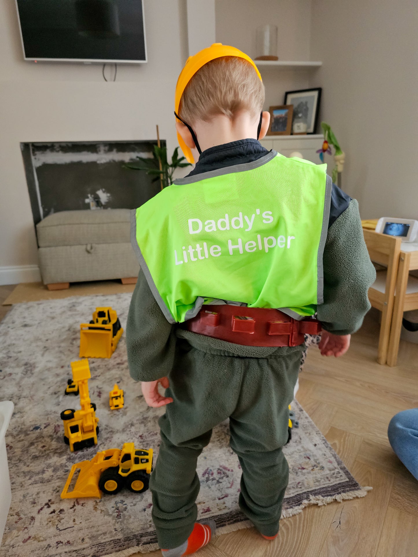 Child wearing hivis role play vest while playing with diggers.