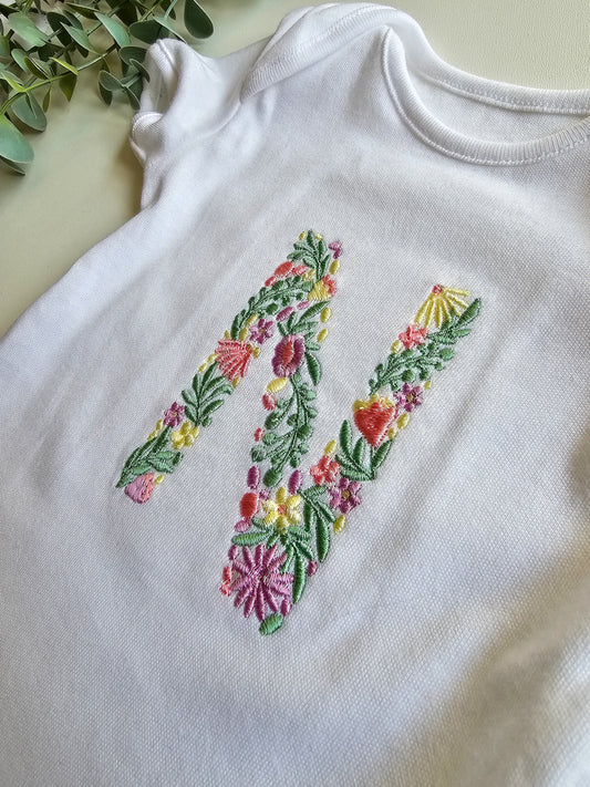 Floral embroidered initial on white baby grow