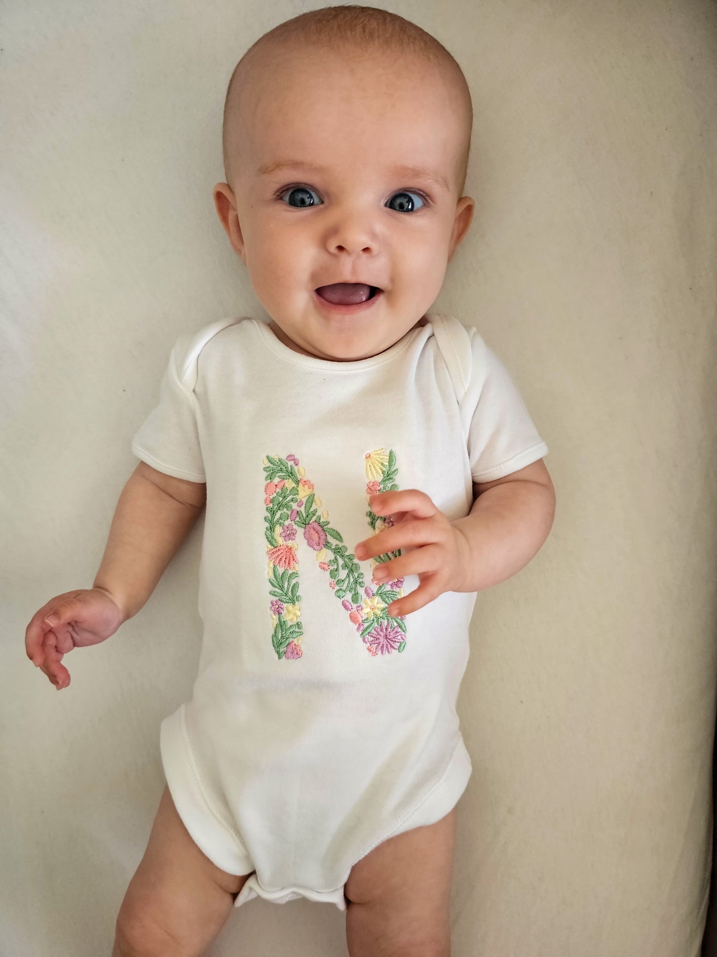 embroidered white baby vest with short sleeves, with floral letter