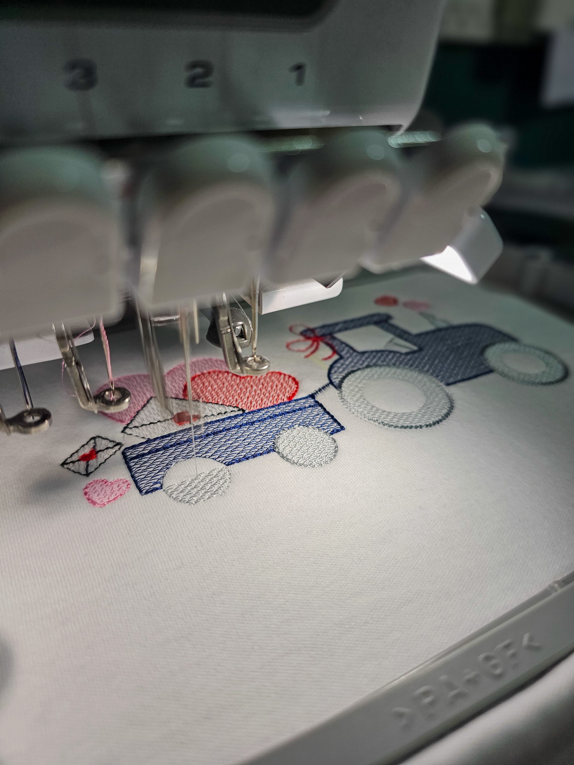 Embroidery machine needle in action with a partially completed design on fabric.