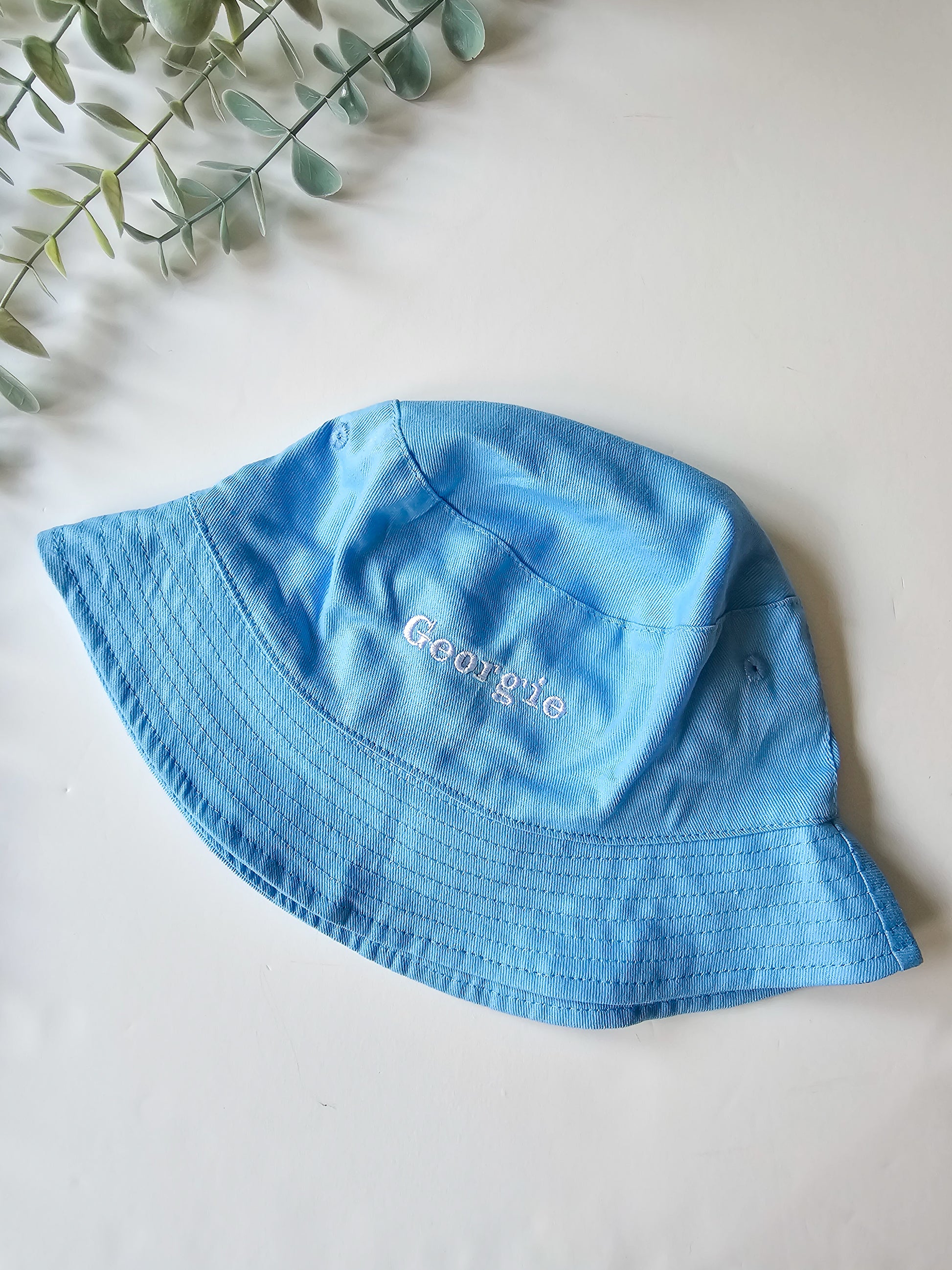 Personalised Blue bucket hat with 'Georgie' embroidery on a light background