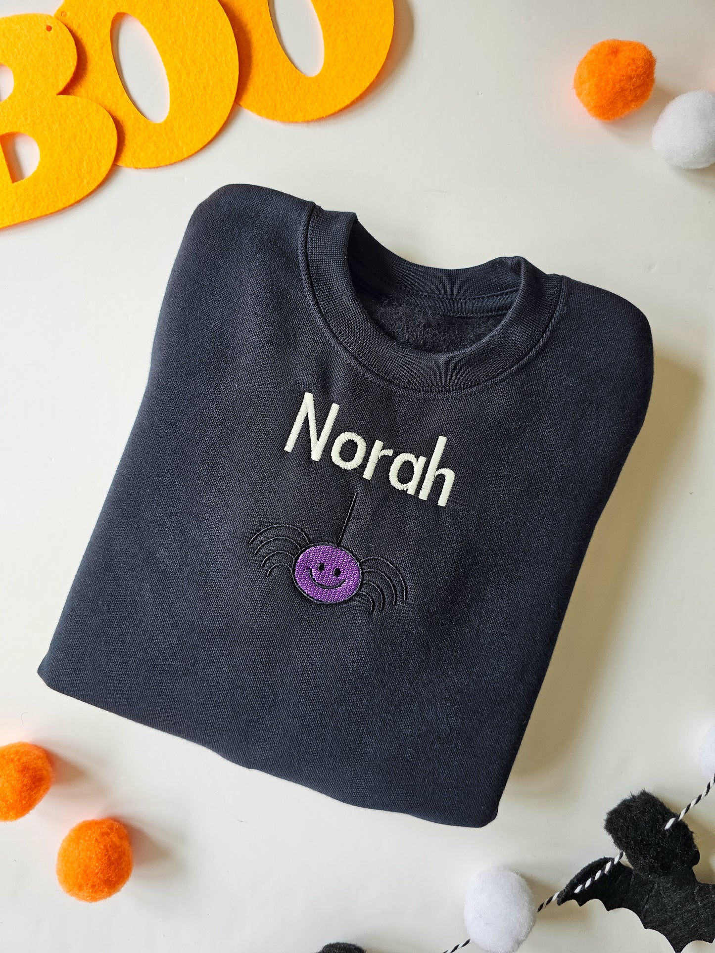 black jumper embroidered with spider and personalised with childs name.