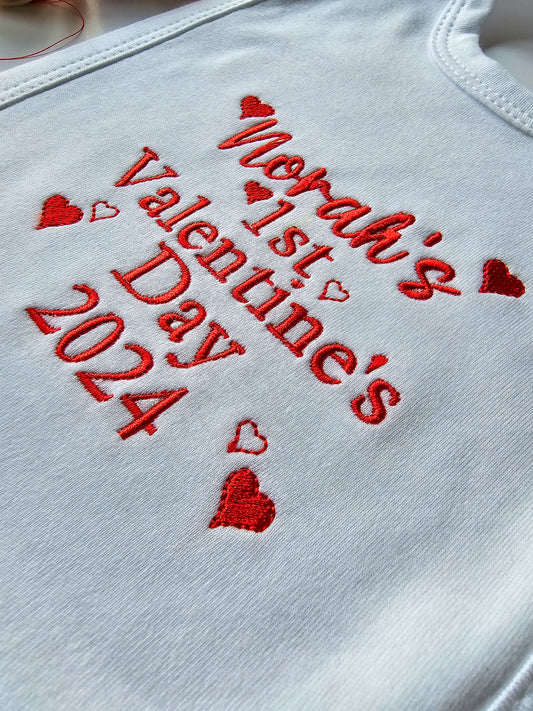 Close up of babys first valentines bib embroidered with small hearts.