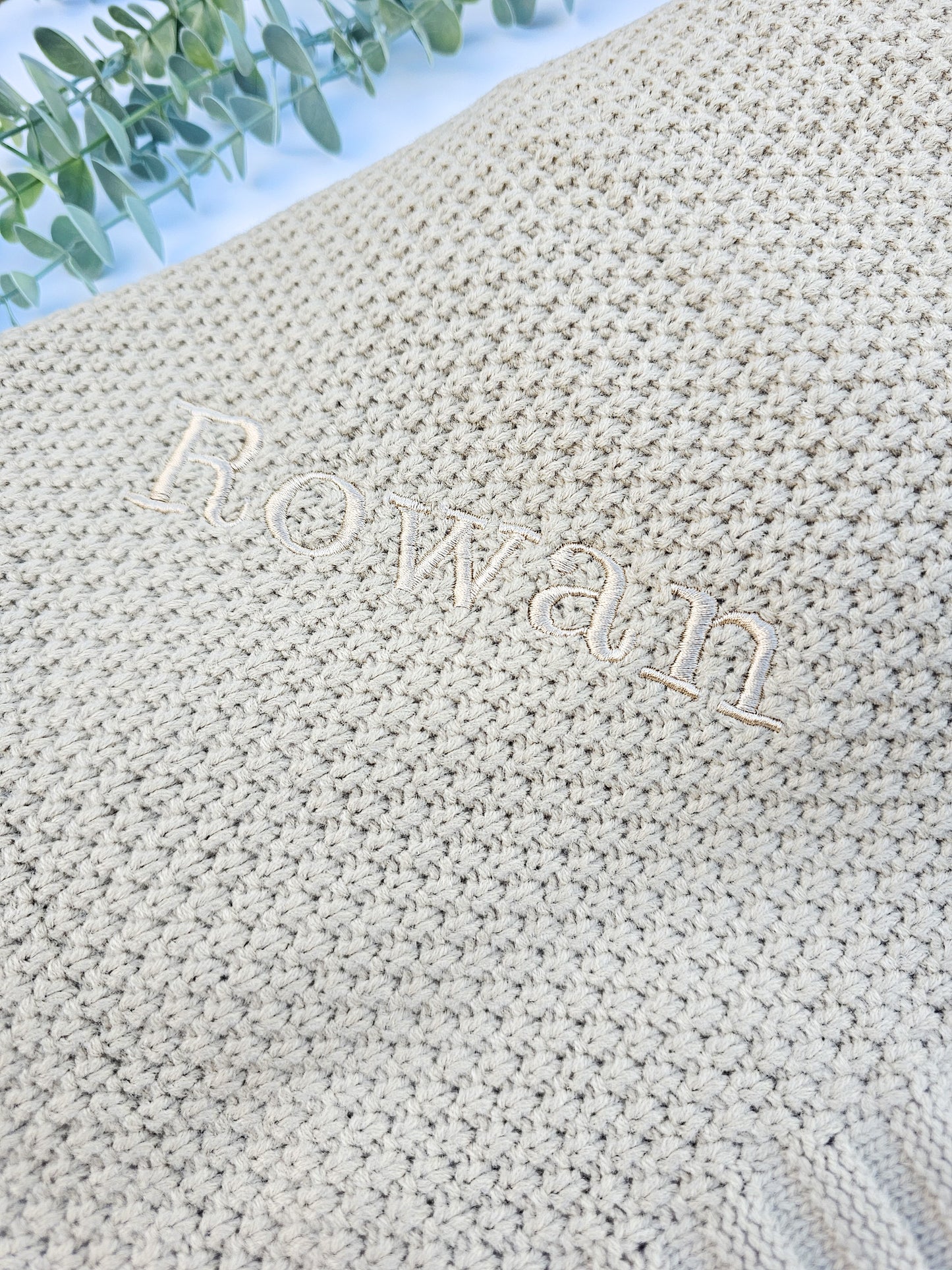 Beige knitted baby blanket personalised with baby's name, embroidered in the same colour thread.
