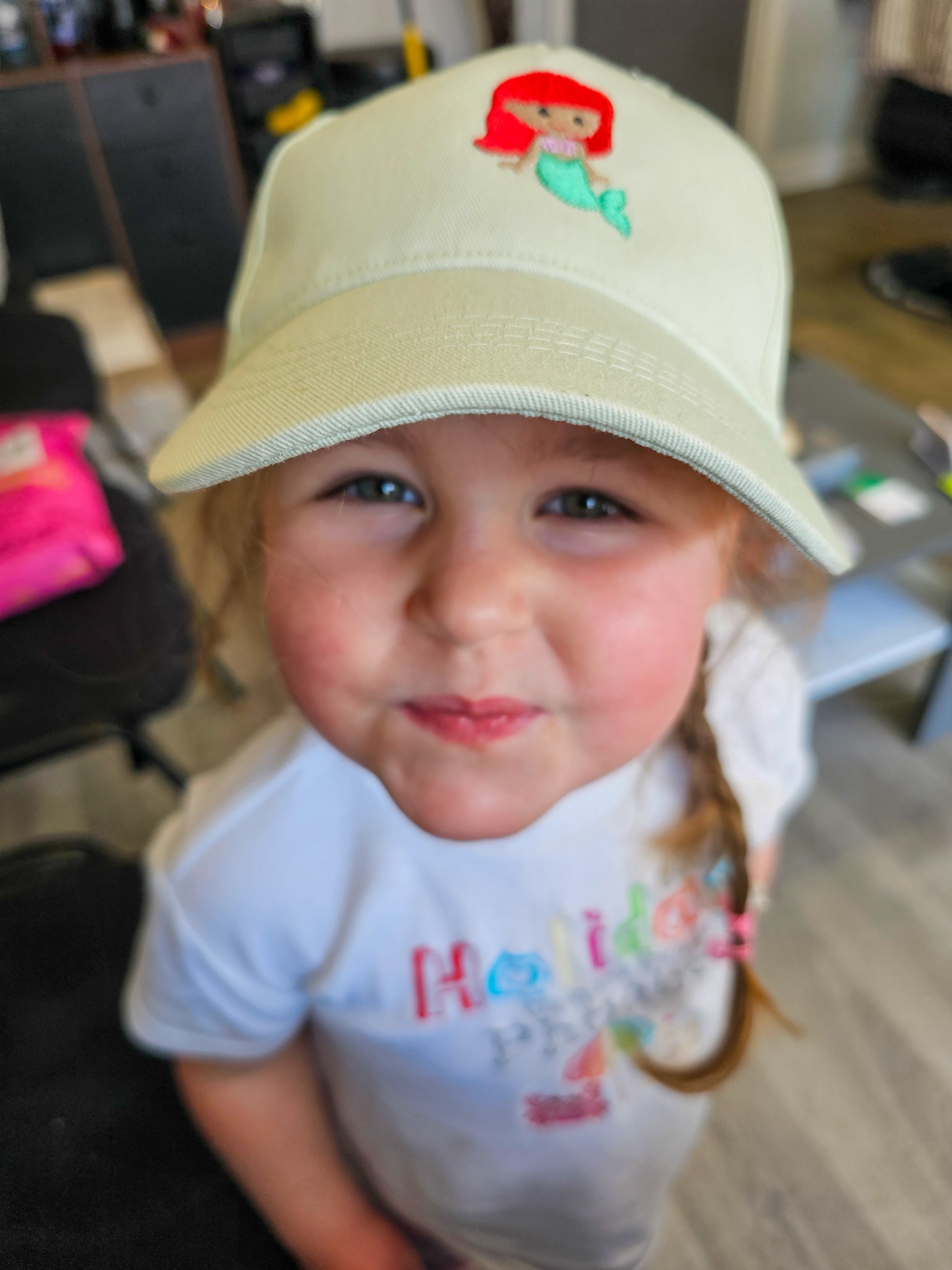 Girl wearing embroidered little mermaid, ariel cap