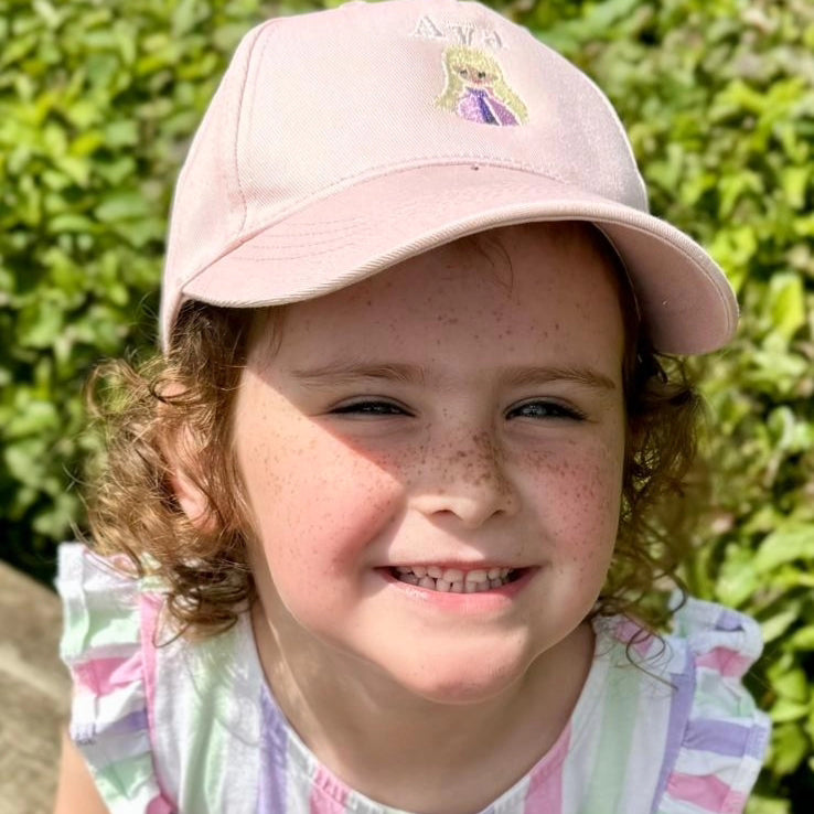 Girl wearing pink embroidered, personalised Rapunzel cap