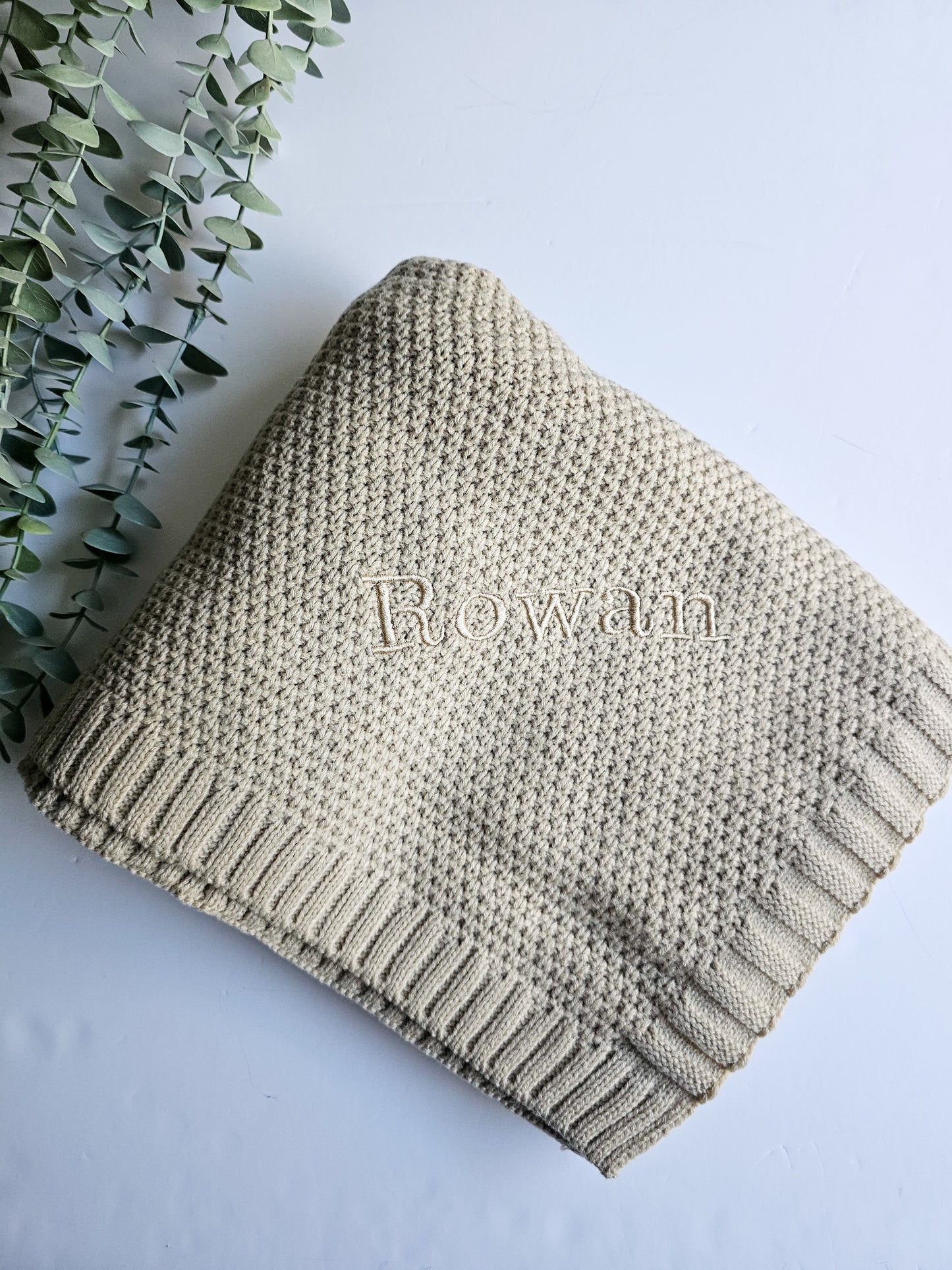 Beige knitted baby blanket personalised with baby's name, embroidered in the same colour thread.