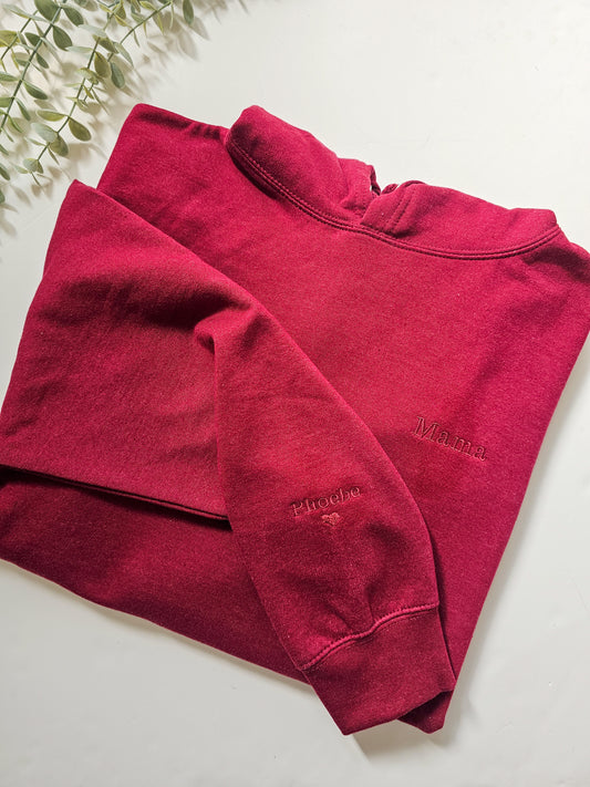 A red personalised embroidered hoodie with the name 'Mama' and a heart symbol on the sleeve, displayed on a white background.