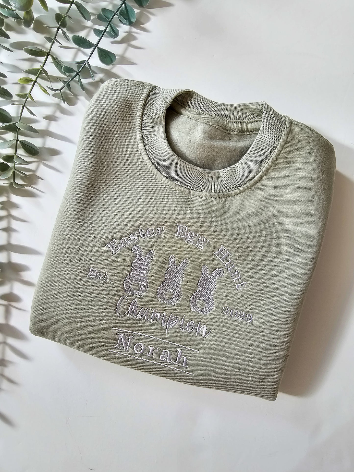 Personalised sage green children’s Easter jumper embroidered with Easter Egg Hunt Champion design and child’s name.