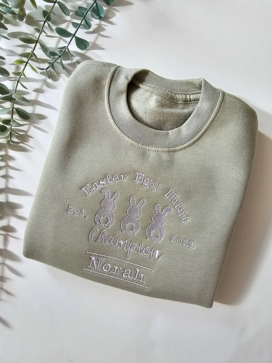 Personalised sage green children’s Easter jumper embroidered with Easter Egg Hunt Champion design and child’s name.