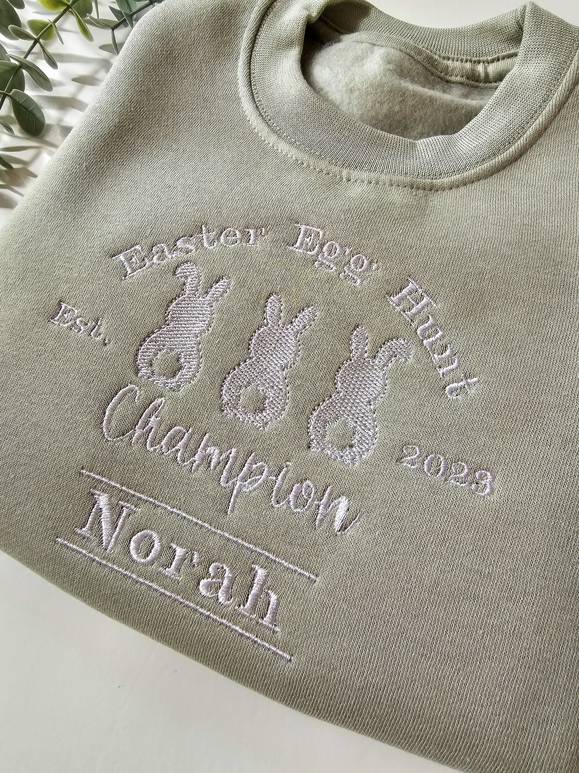 Personalised sage green children’s Easter jumper embroidered with Easter Egg Hunt Champion design and child’s name.