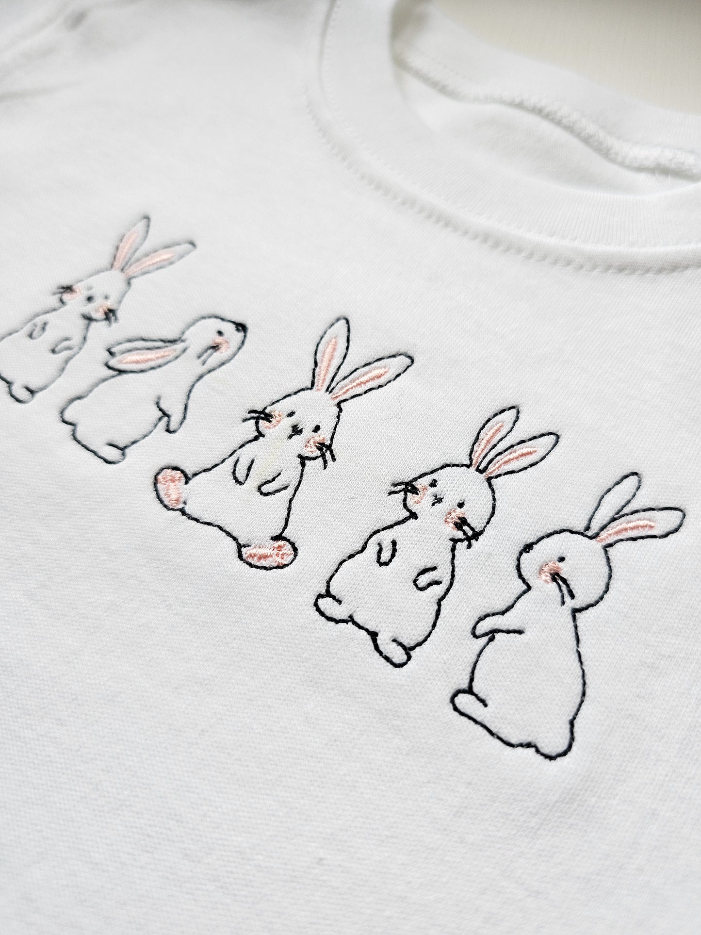 White sweater with embroidered bunnies on a white background
