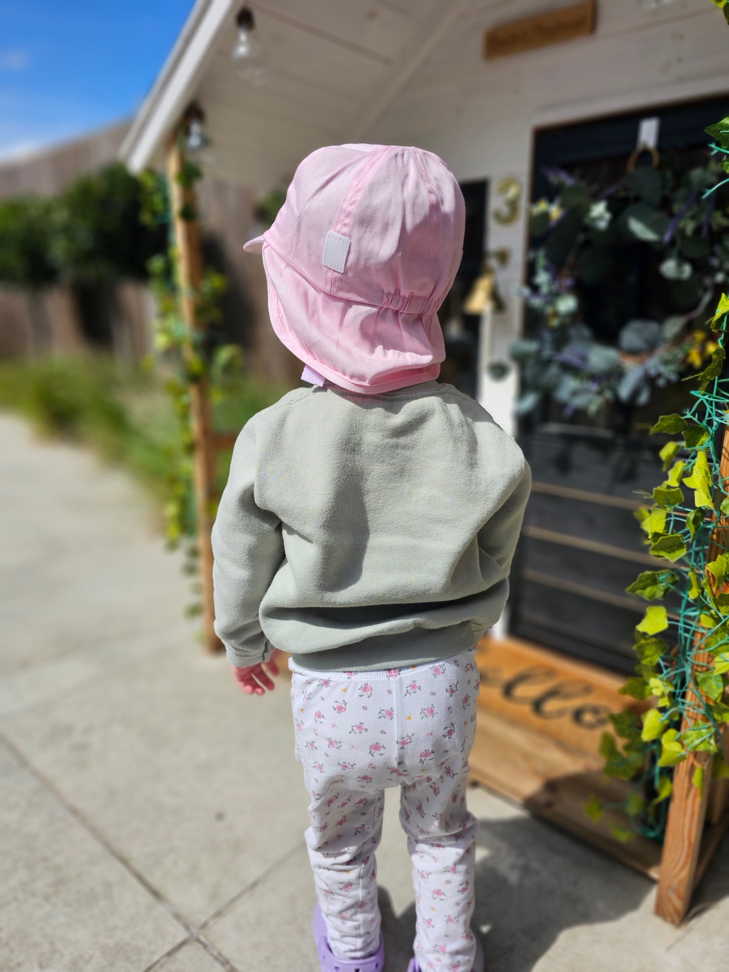 Little girl wearing pink coloured children/toddler/baby personalised embroidered cap with neck cover.