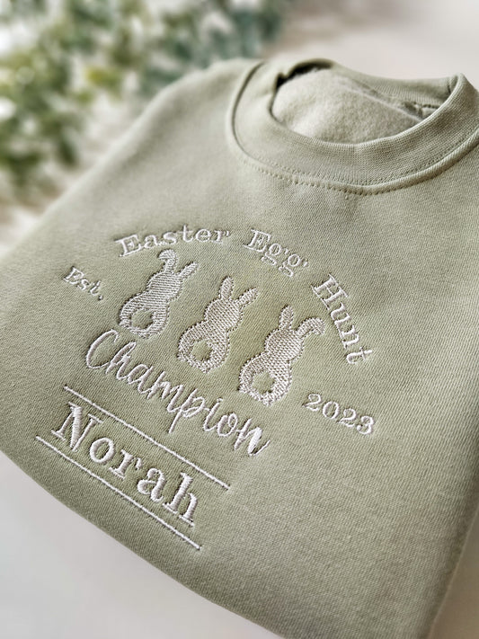 Personalised sage green children’s Easter jumper embroidered with Easter Egg Hunt Champion design and child’s name.
