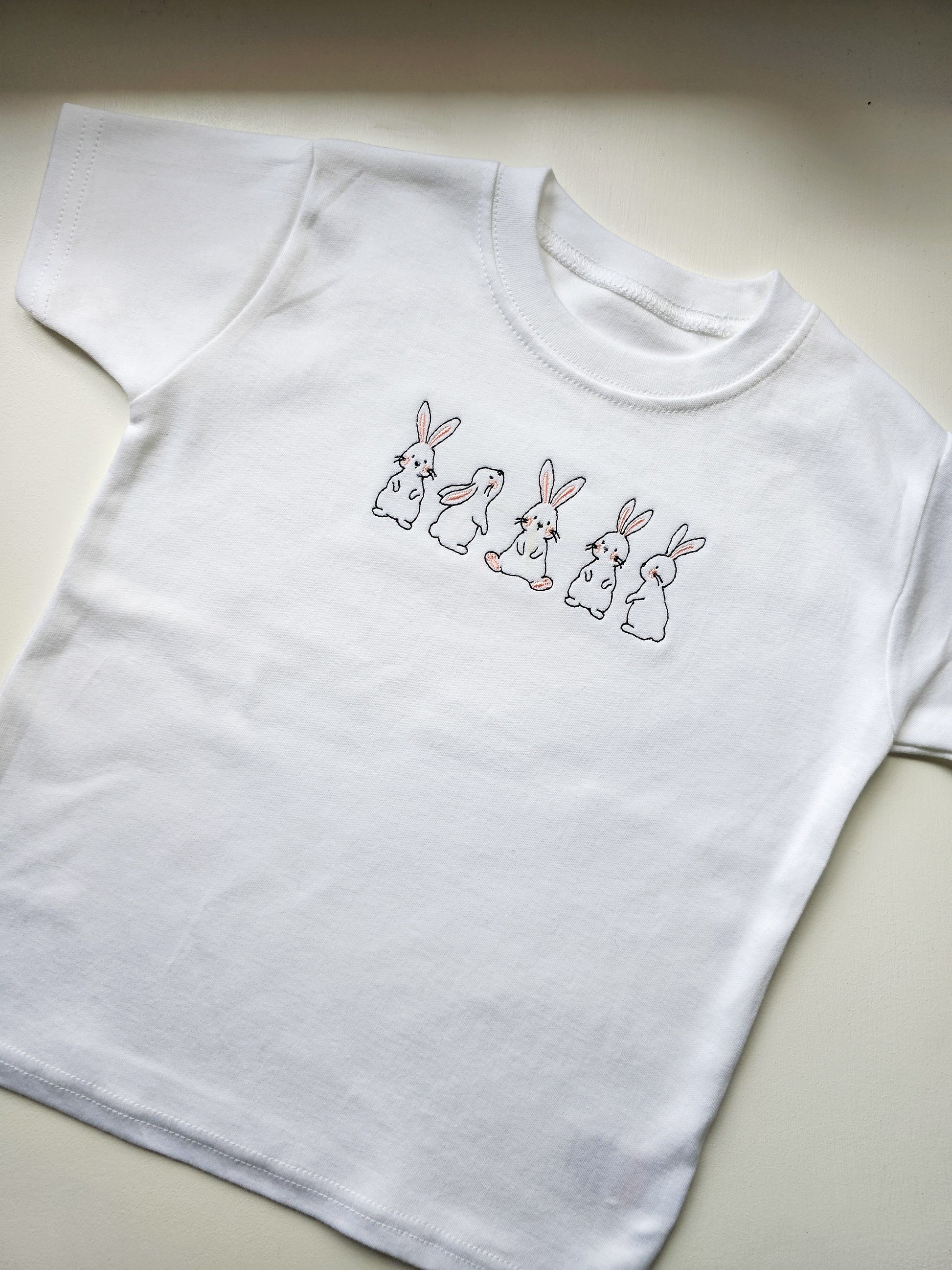 White t-shirt with embroidered bunnies on a light background